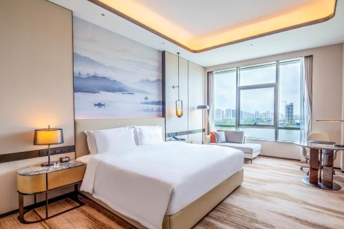 a bedroom with a large white bed and a large window at Pullman Suzhou Taicang in Taicang