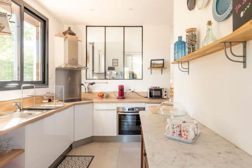 une cuisine avec des armoires blanches et un comptoir dans l'établissement Gîte La Quille - Maison de hameau en Provence pour 4 personnes avec jardin privatif, à Le Puy-Sainte-Réparade