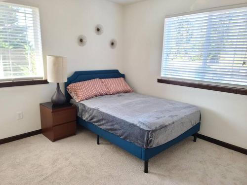 a bedroom with a blue bed and two windows at Spacious and peaceful 4 bedroom home in Everett