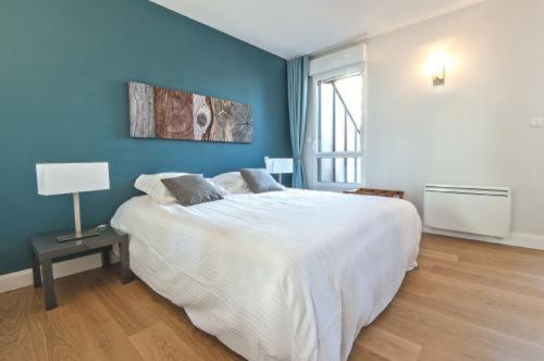 サン・マロにあるRésidence Quai Sud- Le Charcotの青い壁のベッドルーム1室(大きな白いベッド1台付)