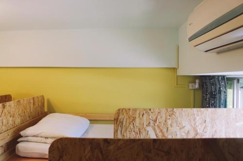 a room with a yellow wall with a bed in it at South Talk B&B in Hengchun