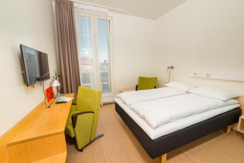 Dormitorio con cama, escritorio y TV en Hotel St. Olav en Trondheim