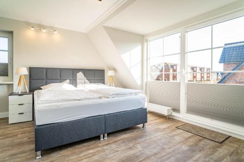 - une chambre avec un grand lit et de grandes fenêtres dans l'établissement Haus Strandoase, à Westerland