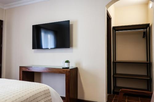 a bedroom with a bed and a television on the wall at Hotel Paseo Santiago in Coroneo