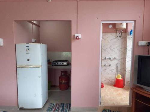 eine Küche mit einem weißen Kühlschrank und einem TV in der Unterkunft Tokari Home Stay in Guwahati