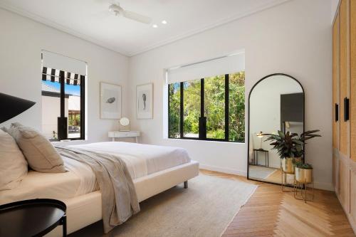 a white bedroom with a large bed and a mirror at Fairway in Goonengerry