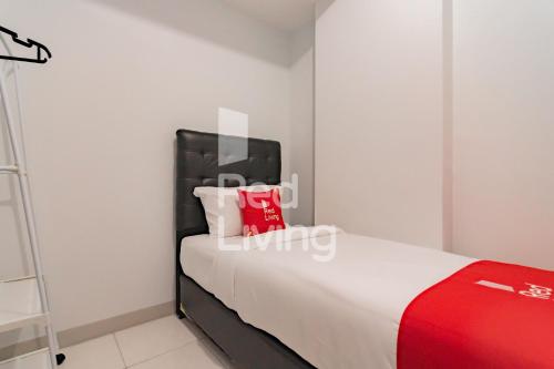 - une chambre avec un lit et une valise rouge dans l'établissement RedLiving Apartemen Mekarwangi Square - M Express, à Bandung