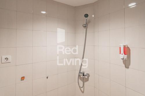 a bathroom with a shower with a red living sign on the wall at RedLiving Apartemen Mekarwangi Square - M Express in Bandung
