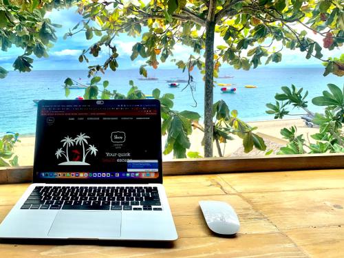 a laptop computer sitting on a table next to a beach at The Henry Resort Taramindu Laiya in Batangas City