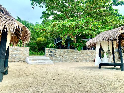 a stone wall with a bench and a thatch roof at The Henry Resort Taramindu Laiya in Batangas City