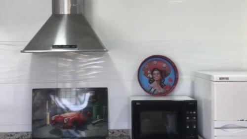 eine Küche mit einer Mikrowelle und einer Uhr an der Wand in der Unterkunft VillavistasB in Hornachuelos