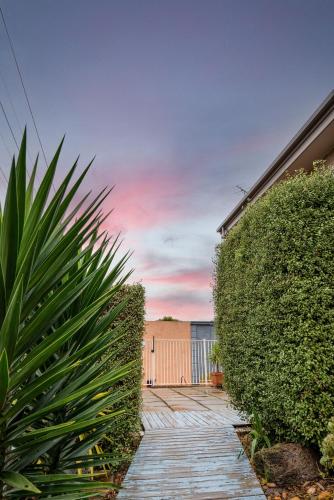 a garden with a hedge and a wooden walkway at The Cosy Room at Arlingtons in Portarlington