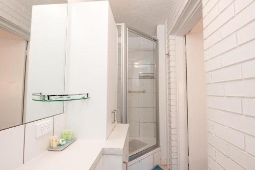 a white bathroom with a shower and a sink at The Cosy Room at Arlingtons in Portarlington