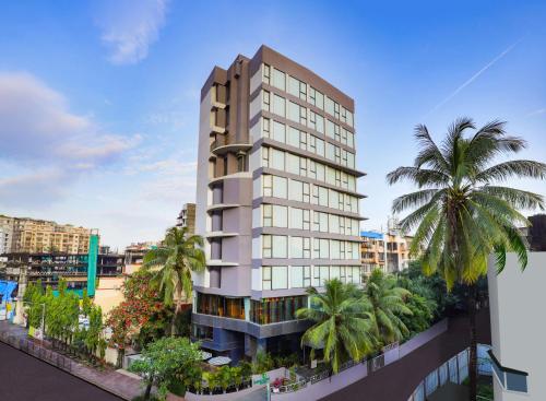 ムンバイにあるLemon Tree Hotel, Kalina BKC, Mumbaiのヤシの木が前に生えている高い建物