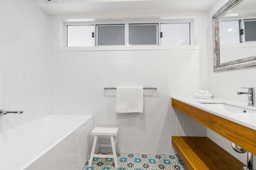 a white bathroom with a sink and a stool at The Estate Main House Byron Bay in Bangalow