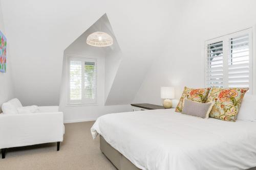 a white bedroom with a bed and a chair at The Estate Main House Byron Bay in Bangalow