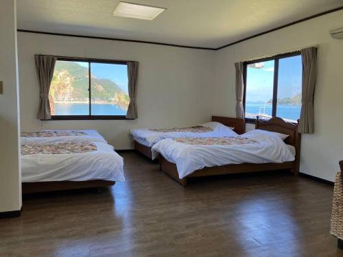 Habitación con 3 camas y 2 ventanas en Sea Tiger Island Inn Shodoshima, en Shodoshima