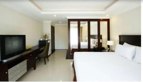 a bedroom with a bed and a desk and a television at Ivory Palace Hotel in Pattaya