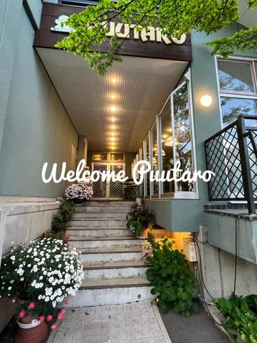 a staircase leading up to a building with flowers at Pension Puutaro in Zaō Onsen