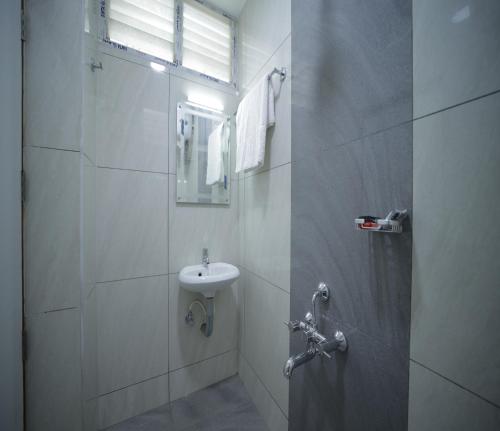 a white bathroom with a sink and a shower at Nadanam Inn in Puducherry