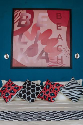 a couch with pillows and a painting on a wall at Belika Beach in Hiriketiya