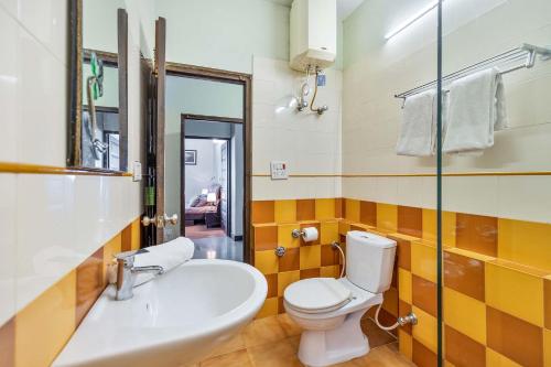 a bathroom with a white toilet and a sink at StayVista at Stonehill Manor with Outdoor Sitting in Dharamshala