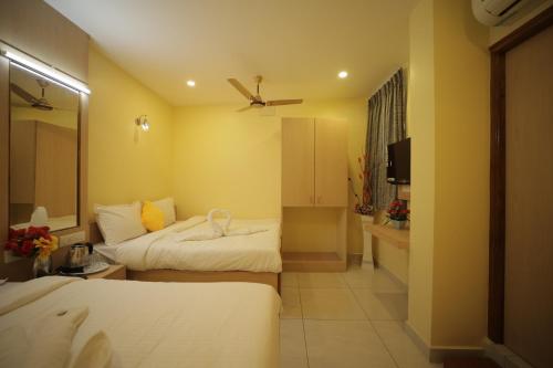 a hotel room with two beds and a bathroom at Nadanam Inn in Puducherry