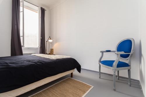 1 dormitorio con 1 cama y 1 silla azul en Appartement le Fighiéra, en Niza