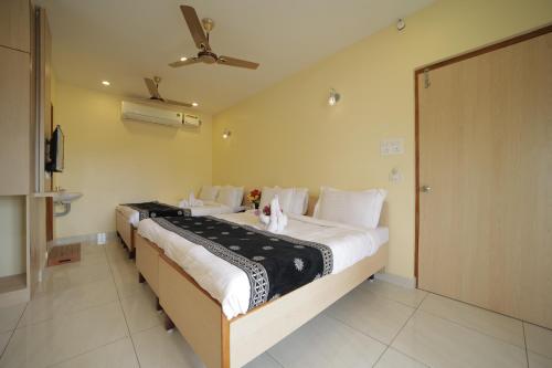 a bedroom with two beds with white pillows at Nadanam Inn in Puducherry