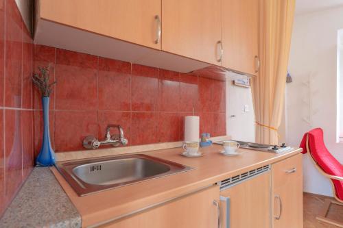 cocina con fregadero y pared de azulejos rojos en Apartman studio Stari Grad - 1 en Stari Grad