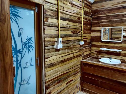 a bathroom with wooden walls and a sink at สายฝนการ์เด้น in Ban On Luai