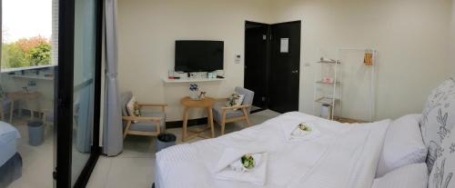 a living room with a bed and a tv at 金門民宿 x 花藝雅築 The Flower Hut in Jinhu