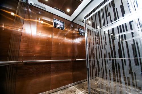 une cabine de douche avec des murs en bois et une porte en verre dans l'établissement Ardager Residence, à Atyraū