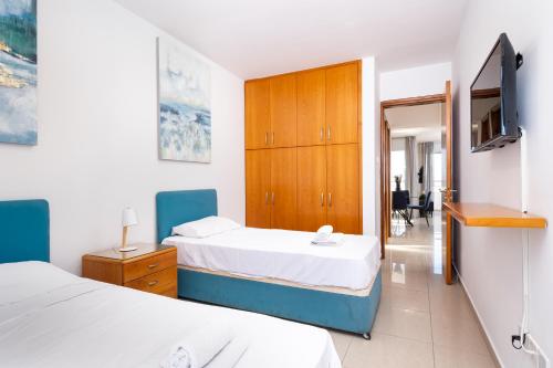 a bedroom with two beds and a television in it at The Saline Views Makenzy in Larnaca