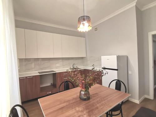 a kitchen with a table with a vase of flowers on it at Сканди-однушка на Пирамиде in Promyshlennyy