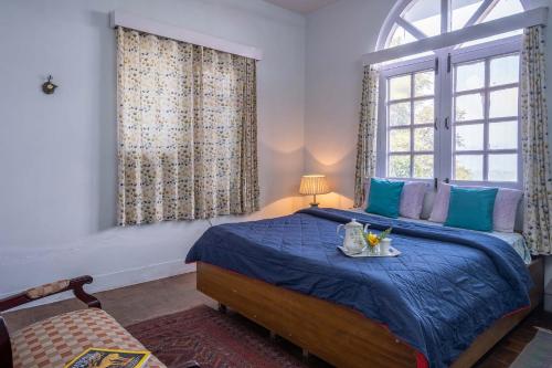 a bedroom with a blue bed and a window at StayVista at Misty Mountains Cottage in Kasauli