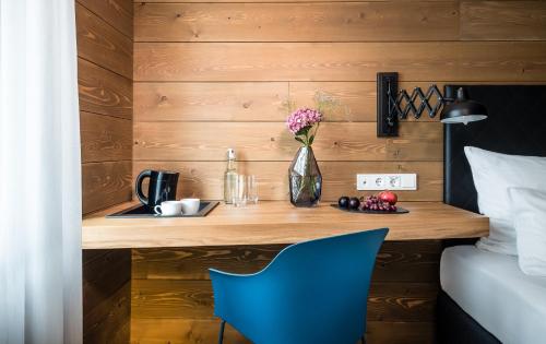 a bedroom with a wooden wall with a desk and a blue chair at Best Western Hotel Das Donners in Cuxhaven
