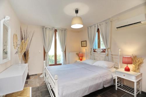 a bedroom with a white bed and two windows at Blue & Green Villa in Panormos Skopelos