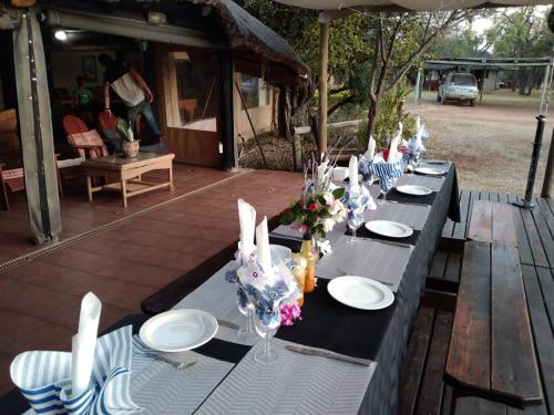 a table set up for a party with plates and flowers at Tranquillity Day Spa & Lodge in Baviaanspoort