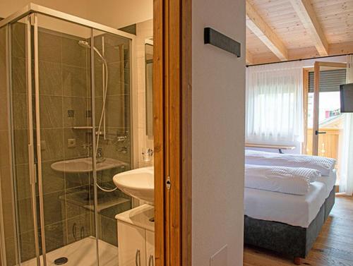 ein Bad mit einem Bett, einer Dusche und einem Waschbecken in der Unterkunft Rodahof in Sexten