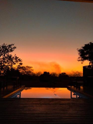 a sunset over a pool of water with stairs at Tranquillity Day Spa & Lodge in Baviaanspoort