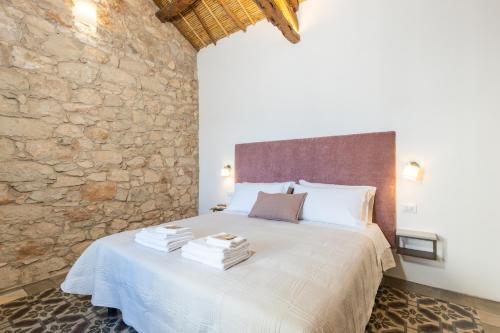 a bedroom with a white bed with a stone wall at Monte Forru in Baunei