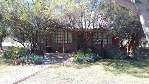 a brick house with trees and flowers in front of it at Tranquillity Day Spa & Lodge in Baviaanspoort