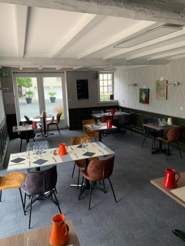 a dining room with tables and chairs and windows at Logis Domaine du Prieuré in Tonnay-Boutonne