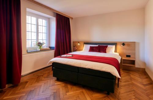 a bedroom with a large bed with red curtains at Erler Koornhuus in Raesfeld
