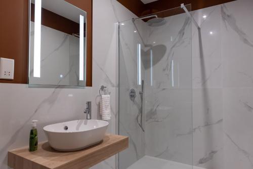 a white bathroom with a sink and a shower at The Carob Tree in Victoria