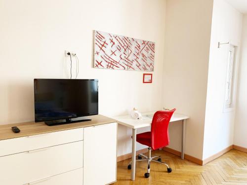 Habitación con escritorio, TV y silla roja. en Rosengarten en Bolzano