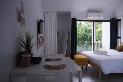 a bedroom with a bed and a table and a window at Baan Trok Bedroom Studio Maikhao in Mai Khao Beach