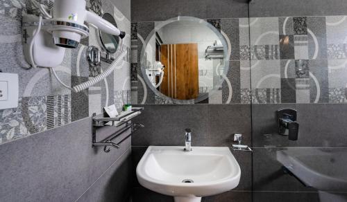 ein Bad mit einem Waschbecken und einem Spiegel in der Unterkunft Royal Tusker Luxury Service Apartments in Mysore