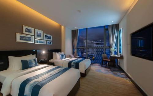 a hotel room with two beds and a television at Queen Ann Nha Trang Hotel in Nha Trang